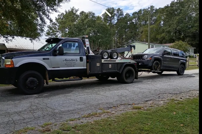Austin's tow truck towing a dark SUV on a neighborhood road